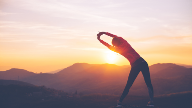 Frau macht Dehnübungen im Sonnenuntergang, symbolisch für Stressabbau und gesenkten Cortisolspiegel