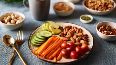 Festlich gedeckter Tisch mit gesunden Snacks wie Nüssen, geschnittenem Gemüse und einer Tasse Tee \u2013 ideale Inspiration für eine stressfreie Weihnachtszeit.