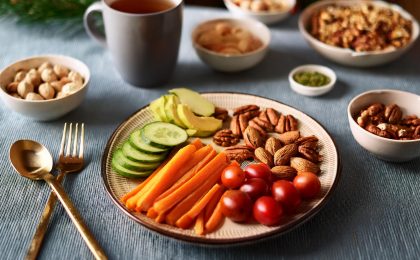 Festlich gedeckter Tisch mit gesunden Snacks wie Nüssen, geschnittenem Gemüse und einer Tasse Tee \u2013 ideale Inspiration für eine stressfreie Weihnachtszeit.