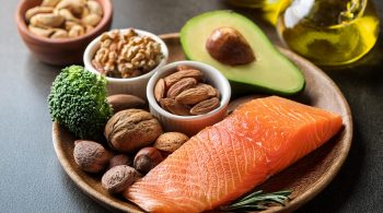 Gesunde Fette: Avocado, Nüsse, Olivenöl und Lachs auf einem Teller – Nährstoffreiche Lebensmittel zur Unterstützung des Stoffwechsels