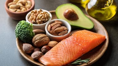 Gesunde Fette: Avocado, Nüsse, Olivenöl und Lachs auf einem Teller – Nährstoffreiche Lebensmittel zur Unterstützung des Stoffwechsels