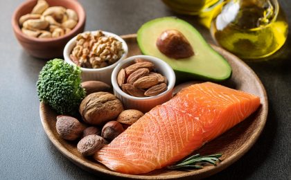 Gesunde Fette: Avocado, Nüsse, Olivenöl und Lachs auf einem Teller – Nährstoffreiche Lebensmittel zur Unterstützung des Stoffwechsels