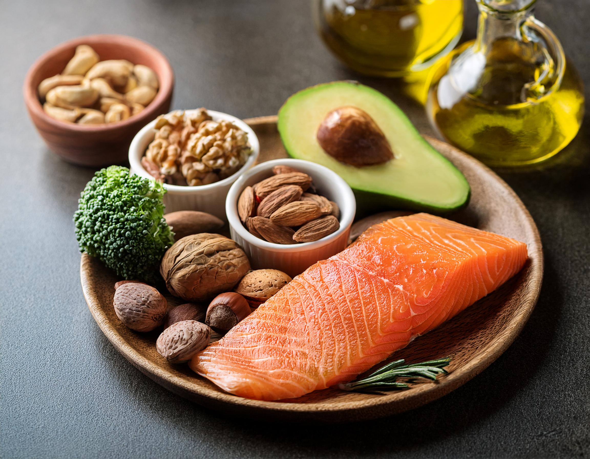 Gesunde Fette: Avocado, Nüsse, Olivenöl und Lachs auf einem Teller – Nährstoffreiche Lebensmittel zur Unterstützung des Stoffwechsels Gesunde Fette: Avocado, Nüsse, Olivenöl und Lachs auf einem Teller – Nährstoffreiche Lebensmittel zur Unterstützung des Stoffwechsels