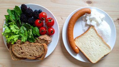 Eine Gegenüberstellung von zwei Tellern: Links Fast Food (Zucker, weißes Brot, Wurst), rechts frische Lebensmittel wie Beeren, Vollkornbrot und grünes Gemüse.