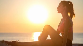 Sportlerin regeneriert nach dem Training im Sonnenuntergang – Symbol für Regeneration und neue Energie im Sport.