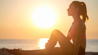Sportlerin regeneriert nach dem Training im Sonnenuntergang – Symbol für Regeneration und neue Energie im Sport.