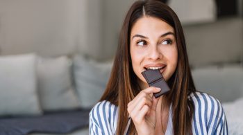 Frau mit gesundem Essen und Schokolade – Heißhunger auf Süßes trotz Sättigung